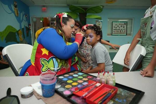 A woman paints the face of a child