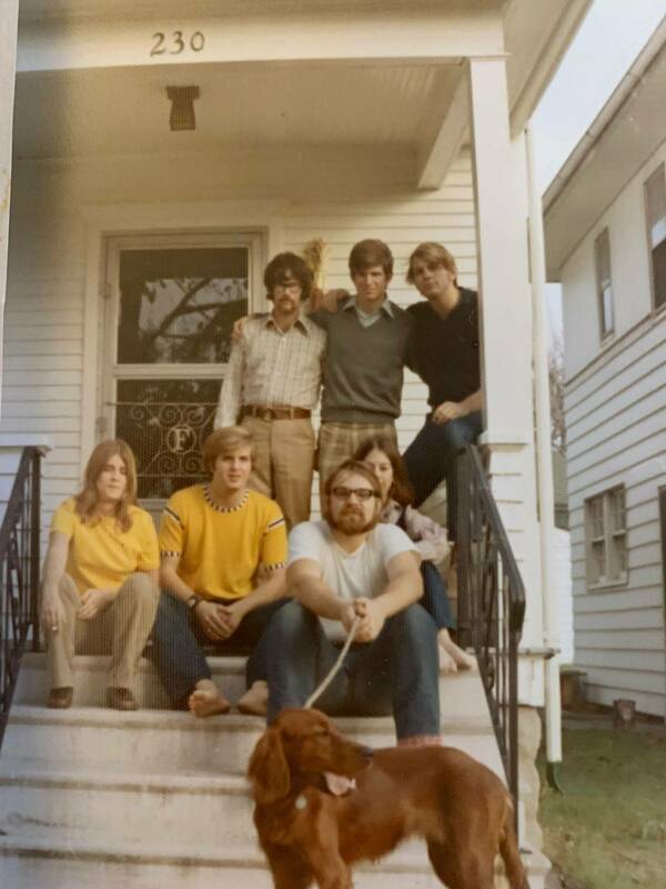 A group of seven Notre Dame students and an Irish setter pose for a photo on the front steps of a house in 1972.