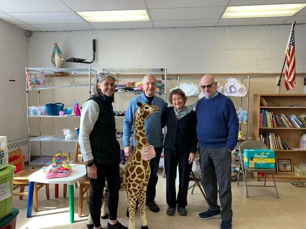David Pais (right) poses with fellow ND grad Robert Shields (second from left) and two women while volunteering at a local women's shelter.
