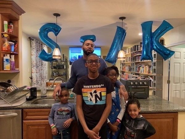 Joseph Earl Thomas poses with four children in front of balloons celebrating the release of his book, Sink.